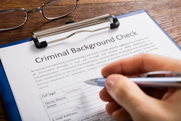 Person filling out a Criminal Background Check form in pen