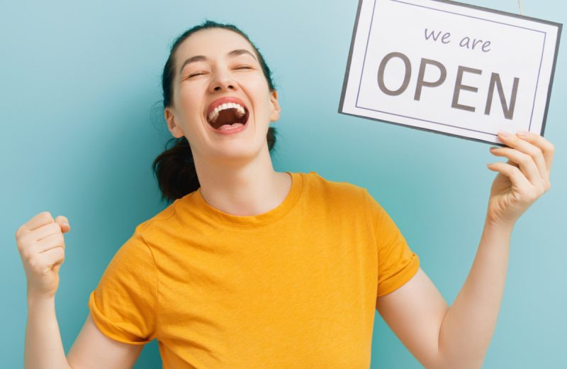 Victorian retail can reopen happy woman celebrates with Open sign